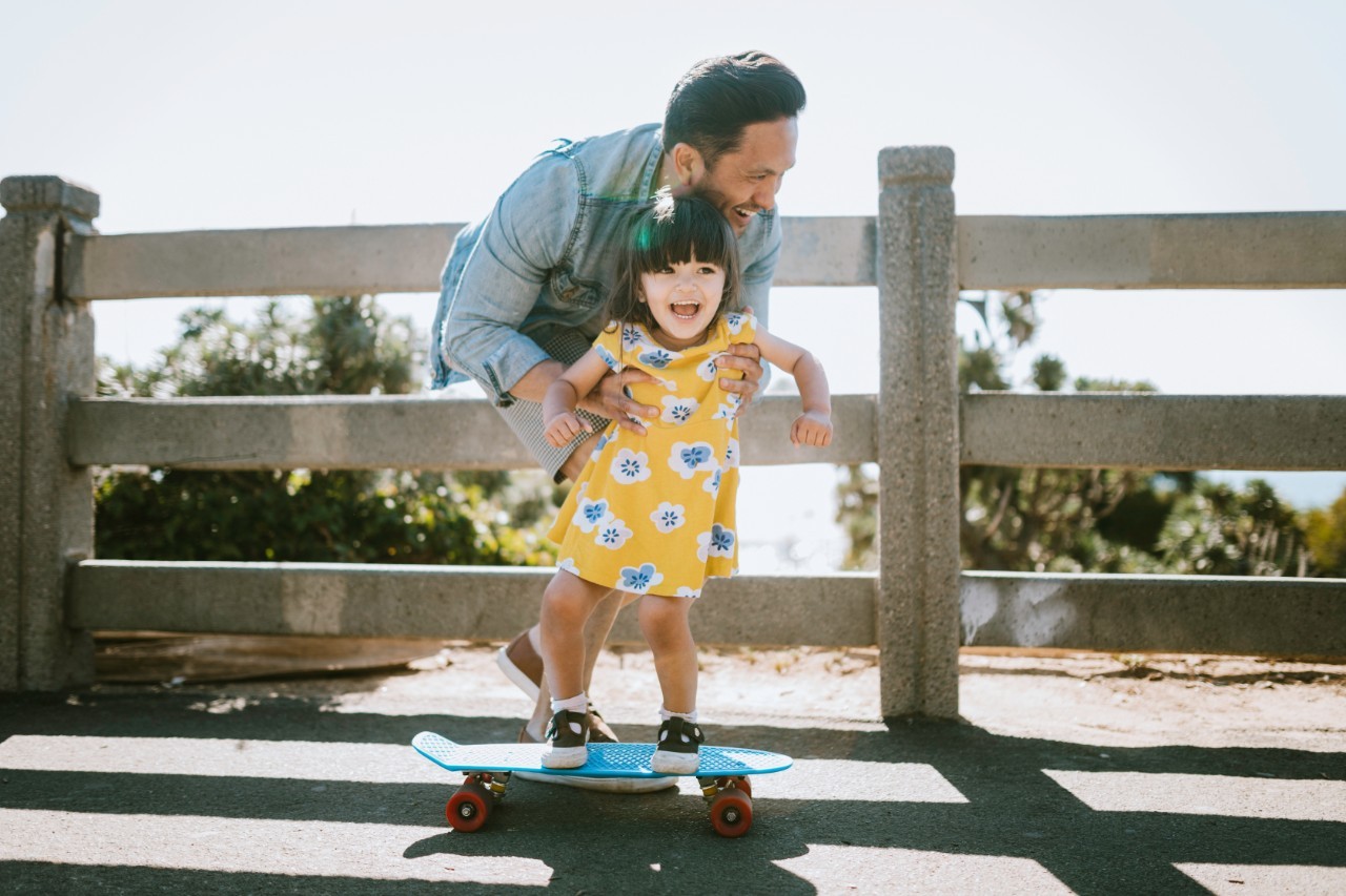 Man helping child on skateboard